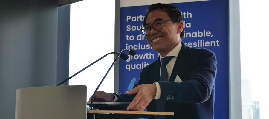 Cambodia Ministry of Economy and Finance Secretary of State, H.E. Meas Soksensan, stands at a lectern with a P4I banner behind him to deliver opening remarks